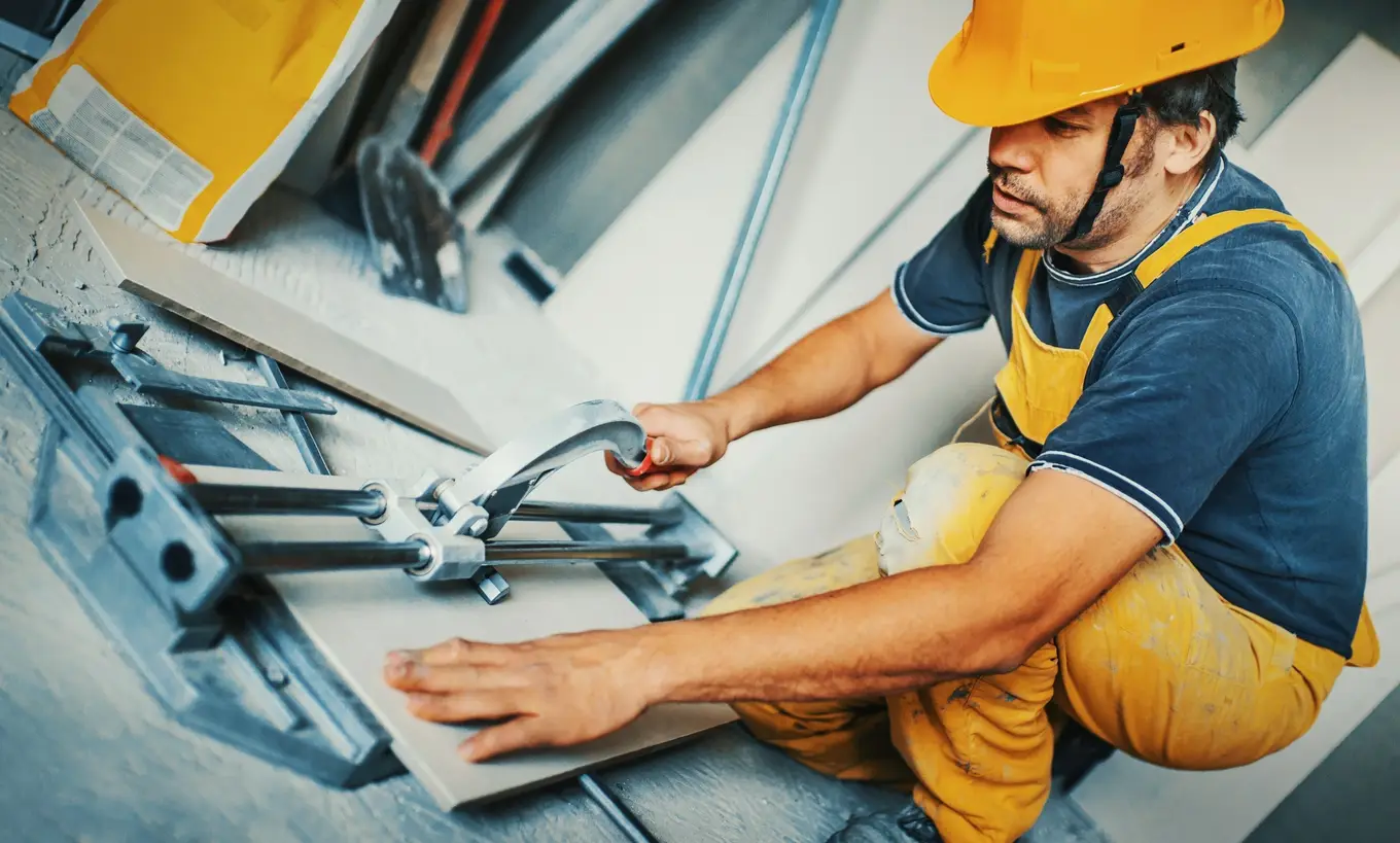 mężczyzna przecinający płytkę podłogową